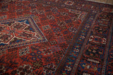Vintage Joshegan carpet detail: red floral field, sapphire blue palmette, and pawn motif borders.