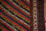 Close-up of the antique Kurdish rug's reciprocating pawn motif border and diagonal vine pattern.