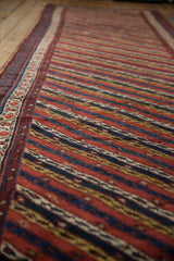 A long perspective view of the antique Kurdish runner, detailing its diagonal channels and side border.