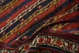 The plush wool pile of an antique Kurdish rug showing diagonal vine patterns and border motifs.
