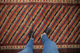 Overhead view showing the scale and texture of the antique Kurdish runner's diagonal vine motif.