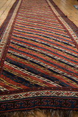 Angled view showing the even pile and intricate diagonal floral motifs of an antique Kurdish runner.