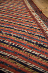 Low angle view of the even pile on an antique Kurdish runner showing diagonal vines in red, blue, and gold.