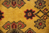 Close-up of the thick, golden wool pile with charcoal and raspberry red floral motifs.