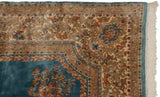 Kerman rug corner with intricate floral border, sky blue field detail, and white fringe.