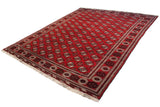 A vintage Bokhara carpet viewed from an angle, showing the repeating geometric guls on a cherry red field.