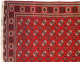 Corner of a vintage Bokhara carpet showing the intricate borders and geometric gul pattern.
