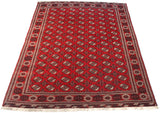 Angled perspective of a vintage Bokhara carpet showing its cherry red field and repeating gul pattern.
