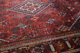 Vintage Joshegan carpet detail: dusty brick field, sapphire blue floral motifs, geometric border.