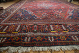Vintage Joshegan carpet's ivory fringe and intricate navy, rust, gold border patterns.