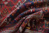 Close-up of a hand-knotted vintage Joshegan carpet, dusty brick and navy floral patterns.
