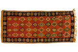Vintage Moroccan runner with colorful diamond medallions on a rust field and wide black border.