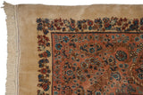 Corner view of a vintage Kerman carpet showing its full pile, floral border, and ivory fringe.