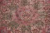 Oversized floral spray medallion of a vintage Persian Kerman carpet in pink, green, and blue.