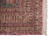 Vintage Kerman carpet corner with a pink and blue Millefleur border and clean ivory fringe.