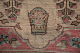 Fine hand-knotted texture showing a Millefleur shrub design in pink, blue, and green.