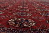 Lustrous red wool pile showing repeating Bokhara-style gul medallions in navy and ivory.