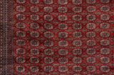 Finely woven gul medallions in navy and ivory against the plush, wine-red field of a Bokhara carpet.