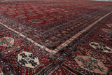 A corner view of a fine Pakistani Bokhara carpet showing intricate borders and plush red pile.