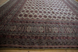 Low angle on a vintage Bokhara carpet, showing the plush pile and detailed geometric borders.
