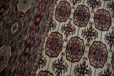 Intricate border pattern beside the ivory field with red and navy elephant footprint motifs.