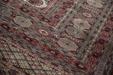 The plush, finely knotted pile of a vintage Bokhara rug showing detailed gul motifs.