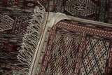 Backside corner of the vintage Pakistani carpet with its fringe, selvage, and an original fabric tag.