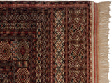Corner of a vintage Pakistani rug showing its intricate geometric borders, side selvage, and ivory fringe.