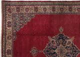 Corner detail of a vintage Oushak carpet showing a navy blue lattice spandrel on a cherry red field.