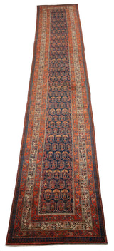 Angled view down the length of a vintage Hamadan runner with repeating boteh motifs on a navy field.