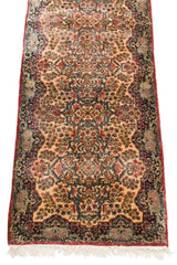 Vintage Kerman runner viewed at an angle, showing its ivory field and dense millefleur pattern.