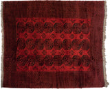 A vintage Afghani Ersari carpet in dusty brick red with repeating oversized charcoal gul motifs.