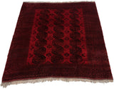 Angled view of a vintage Afghani Ersari carpet with its triple column of red and black gul motifs.