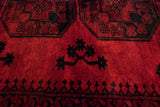 Detail of the full wool pile on a vintage Afghani carpet with red and black gul motifs.