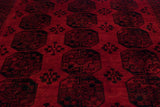 Angled close-up of the vintage carpet's plush red pile and traditional black gul pattern.