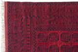Corner of a vintage Ersari rug showing its cherry red and navy geometric borders and intact side selvage.