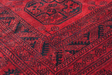 The full, plush wool pile and sharp geometric borders of a vintage red and navy Afghani carpet.