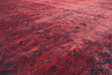 Angled view showing the lustrous sheen of the cherry red and navy wool pile on a vintage Ersari carpet.