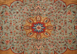 Close-up of the Tabriz carpet's central medallion featuring gold, red, and blue on a seafoam green floral field.