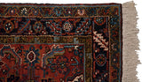 Corner of a vintage Mehrivan runner with a navy serrated leaf border and intact ivory fringe.