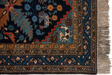 Vintage Ardebil runner corner: navy field, sky blue border, red serrated edge, ivory bird, and fringe.