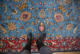Intricate hunting scene on a vintage Qom carpet featuring tigers on a sky blue field and a detailed wine red border.