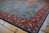 Corner of a vintage Qom carpet showing hunting scenes in the red border and floral blue field.