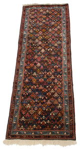 Long angled view of a vintage Ardebil runner showing the repeating geometric floral lattice pattern.