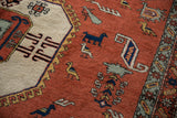 Terracotta field of vintage Meshkin rug featuring geometric birds, animals, and ivory medallion.