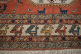 Vintage Persian Meshkin carpet detail showing finned bird border and terracotta field with animals.