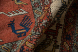 Folded vintage Meshkin carpet, terracotta field, blue bird, and finned geometric border.