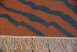 Hand-woven Indian Kilim rug in pale rust and charcoal tiger stripe pattern with natural fringe.