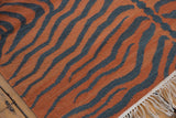 Textured pale rust and charcoal tiger stripe kilim weave showing selvage and white fringe.