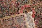 The reverse weave, detailed floral pile, and ivory fringe of a vintage Kerman carpet.